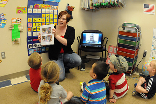 Rachel Clarke, the associate executive director of the Fargo, N.D., YWCA, shows photos of deployed military members as her husband, U.S. Air Force Master Sgt. Josh Clarke, of the 119th Security Forces Squadron, North Dakota Air National Guard, appears on a laptop computer so their son, Wyatt (in hat) and his class of fellow preschoolers at the YWCA Cass Clay can get a chance to communicate with him at his deployed location in Afghanistan via Skype May 23, 2013. The preschool class has been sending packages to the deployed Airmen and Master Sgt. Clarke is communicating his appreciation to the students using the internet. (U.S. Air National Guard photo by SMSgt. David H. Lipp/Released)